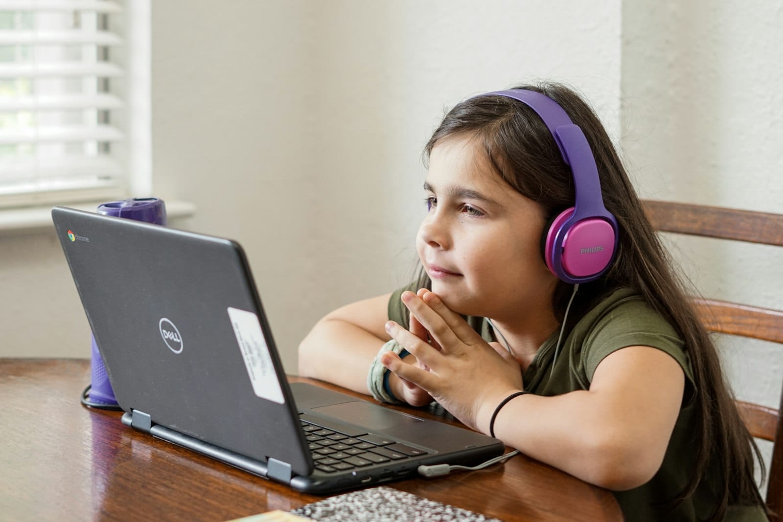 Enfant suivant un cours en ligne avec un casque devant un ordinateur portable