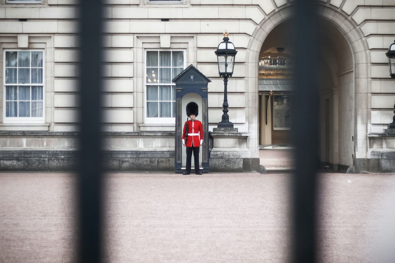 Garde royal en tunique rouge et bonnet en peau d'ours devant Buckingham Palace à Londres