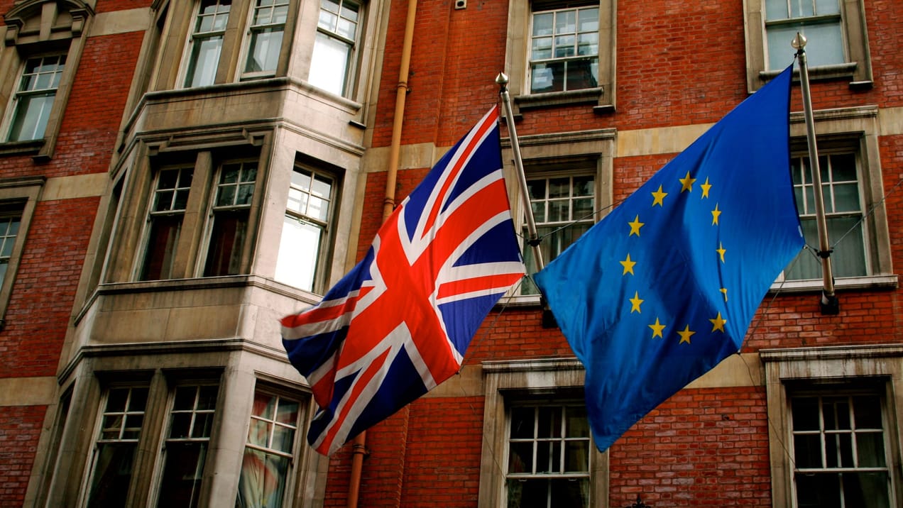 Le drapeau britannique et le drapeau européen flottent côte à côte sous un ciel nuageux à Londres.