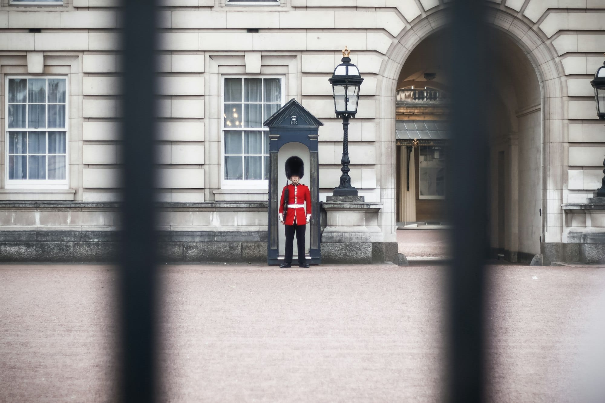 Garde royal en tunique rouge et bonnet en peau d'ours devant Buckingham Palace à Londres